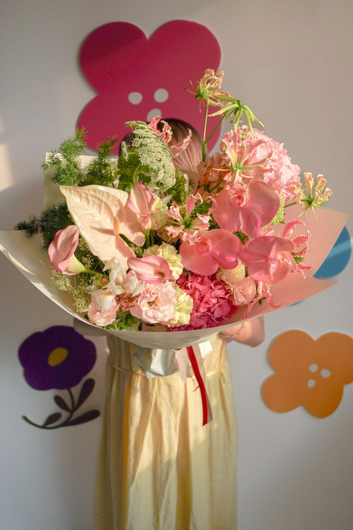 Person holding a bouquet of flowers against a wall with colorful shapes mother's day flower | size:Classic - 35cm